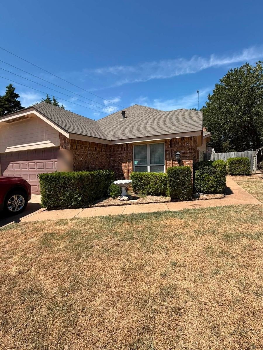 Before: overgrown shrubs along the front of a brick home