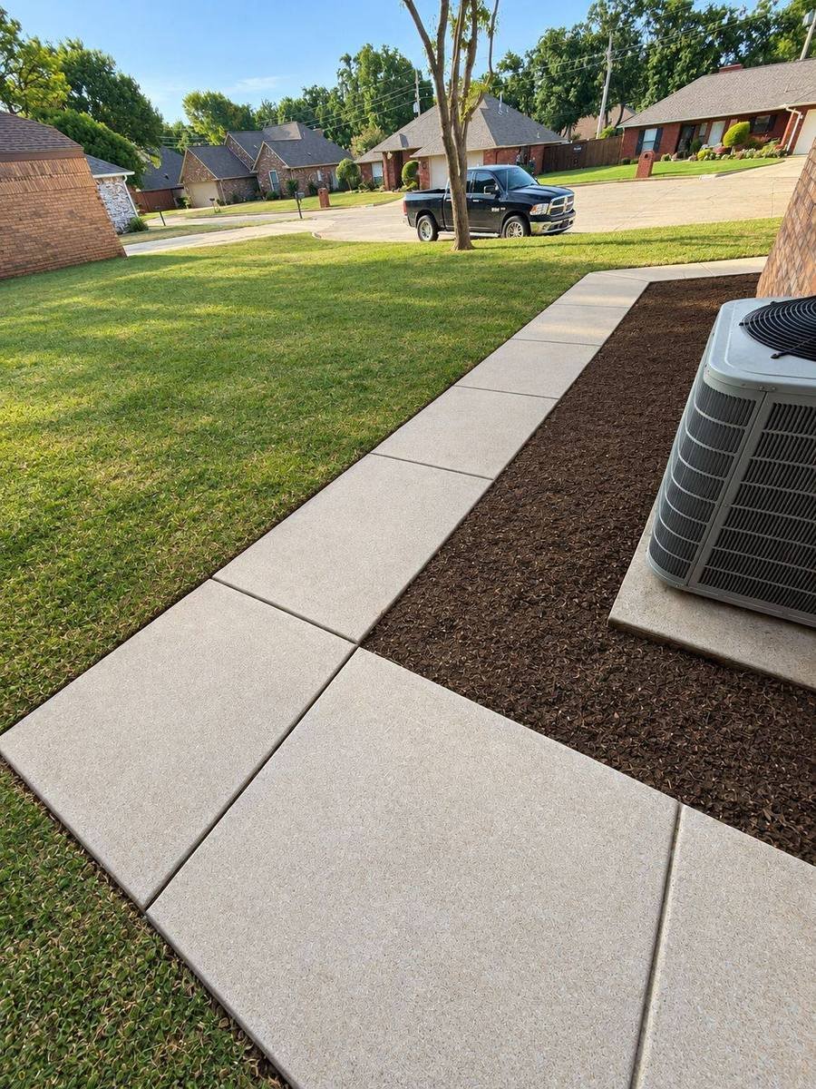 Clean concrete walkway beside a freshly mowed lawn and mulch bed