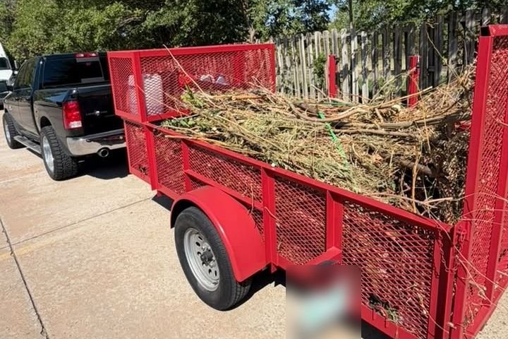 Red trailer loaded with brush and limbs ready to haul away