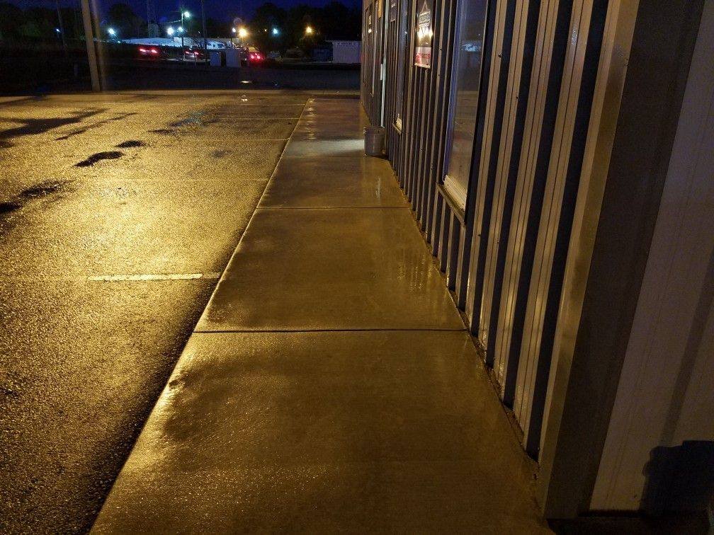 Freshly pressure-washed storefront sidewalk at night